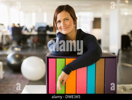 Porträt von zuversichtlich Geschäftsfrau stützte sich auf Ordner Rack im Büro Stockfoto