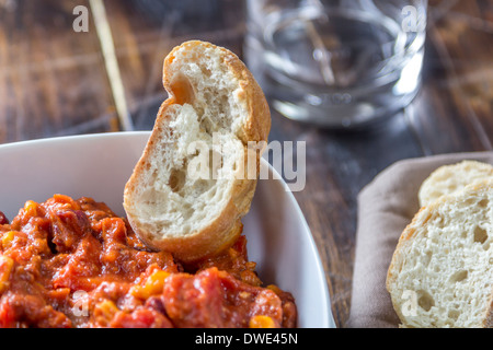 Schüssel mit Chili Con Carne auf einem Holztisch mit etwas Brot geringe Schärfentiefe Stockfoto
