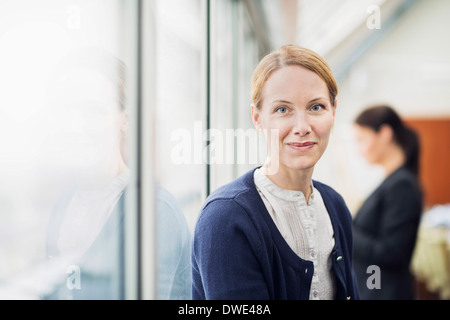 Porträt von zuversichtlich Geschäftsfrau mit Kollegen im Hintergrund im Büro Stockfoto