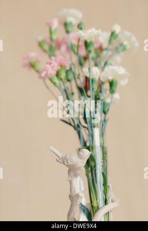 auf abstrakte hellen Hintergrund zartes Bouquet von rosa und weißen Nelken in einer Glasvase mit Vögel Stockfoto