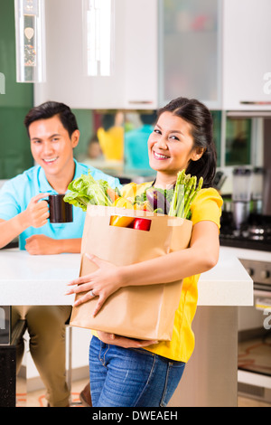 Junge hübsche Asiatin kommt vom Einkaufen nach Hause Stockfoto