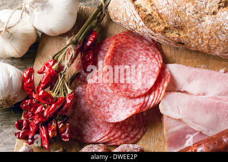 Draufsicht auf Satz von Schinken und Salami mit rote scharfe Chilischoten auf Holzbrett serviert. Stockfoto