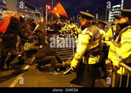 Dublin, Irland. 6. März 2014. Garda Offiziere (irische Polizei) zurückziehen, die Metall-Schranke. Die schwarz-Block Anarchisten und Gardai Offiziere (irische Polizei) ziehen auf dem Metall. Kleine Schlägereien brach zwischen Gardai (irische Polizei) und Demonstranten, nachdem ein Block von schwarzen Block Anarchisten versucht, die Polizeiabsperrung durchbrechen. Zwei Demonstranten wurden verhaftet. Bildnachweis: Michael Debets/Alamy Live-Nachrichten Stockfoto