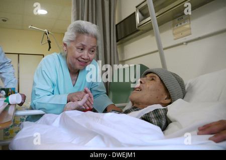 Maryknoll Krankenhaus, Kowloon HONG KONG Mariä. Schwester Marilu Limgenco Besuch eines Patienten. Stockfoto