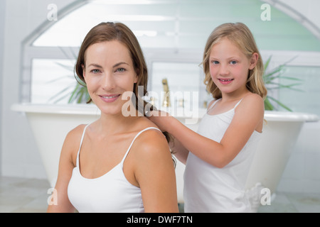 Niedliche kleine Mädchen Flechten Mutters Haare im Bad Stockfoto
