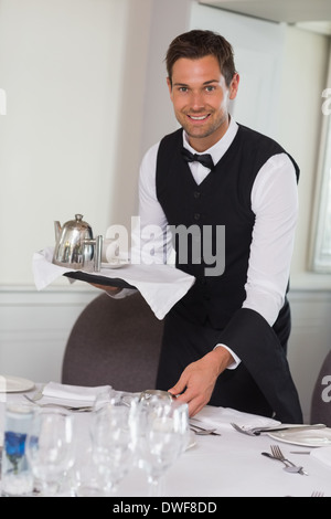 Glücklich Kellner mit Tablett und Einstellung Tabelle Stockfoto