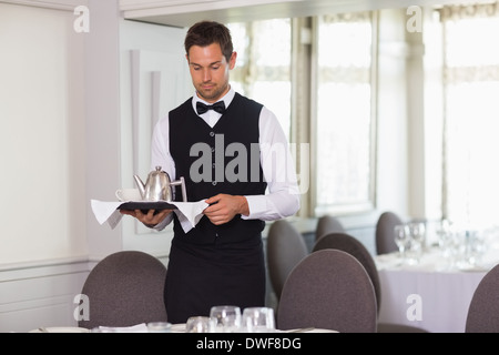 Hübscher Kellner mit Tablett und Einstellung Tabelle Stockfoto