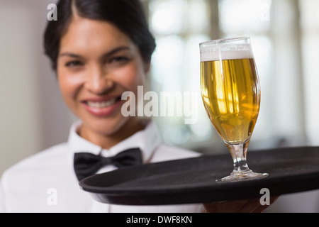 Hübsche Kellnerin hält Tablett mit Glas Bier Stockfoto