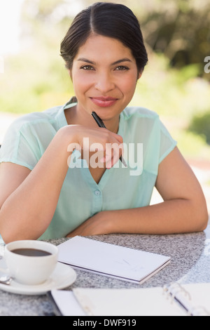 Lächelnde Geschäftsfrau mit Kaffee und planen ihre Woche Stockfoto