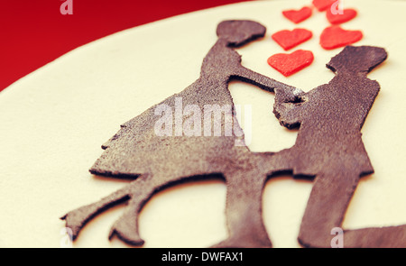 Weiße Runde Kuchen auf rotem Grund, verziert mit männlichen und weiblichen Silhouette von Zucker auf die Oberseite. Stockfoto