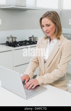 Konzentrierte Geschäftsfrau mit Laptop in der Küche Stockfoto