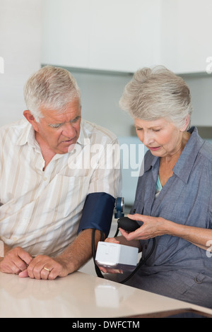 Ältere Frau, die Überprüfung ihrer Ehemänner Blutdruck Stockfoto