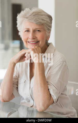 Glückliche ältere Frau am Tisch sitzen Stockfoto