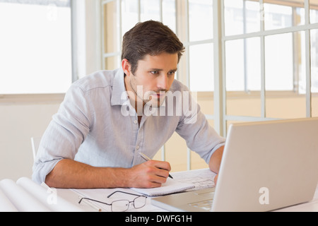Geschäftsmann, arbeiten an Blaupausen und Laptop im Büro Stockfoto
