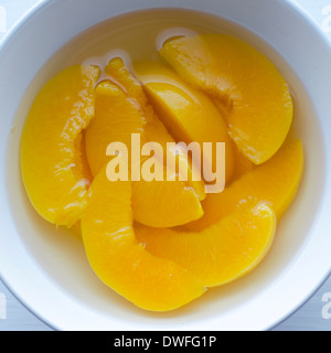 Eine Schüssel mit Pfirsich Scheiben in ein Glas Traubensaft. Stockfoto