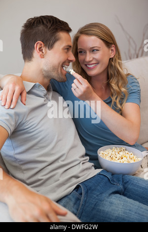 Junge Frau, die Fütterung Mann Popcorn auf sofa Stockfoto