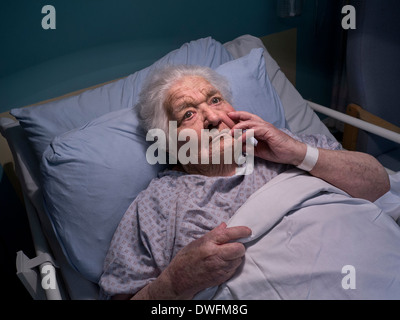 ÄLTERE DAME GEDÄCHTNISPFLEGE KRANKENHAUSBETT PENSIVE VERWIRRTE DEMENZ sehr ältere Frau im Alter von 100 Jahren in Gedanken in der Krankenhausstation Bett in der Nacht Stockfoto