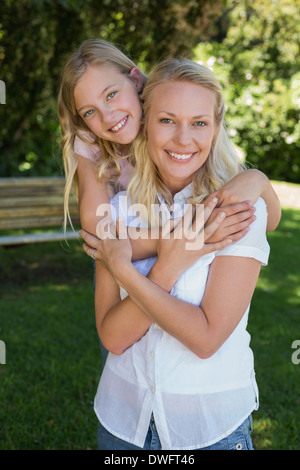 Mädchen, die Mutter von hinten umarmen, im park Stockfoto