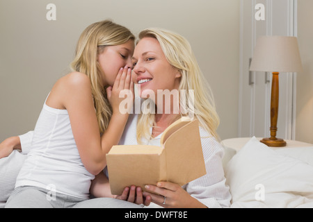 Mädchen, die Geheimnisse zu teilen, mit Mutter im Bett Stockfoto