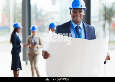 lächelnde afrikanische Architekten halten blau Drucken im Büro Stockfoto