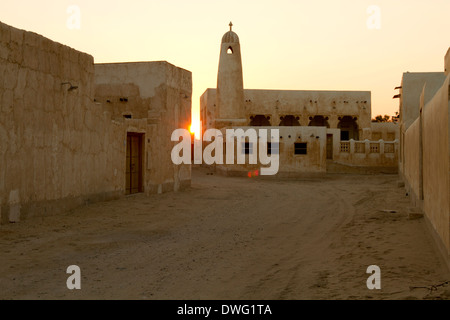 Sonnenuntergang am traditionellen Häusern und Minarett neben Strand in Al Wakra, Katar Stockfoto