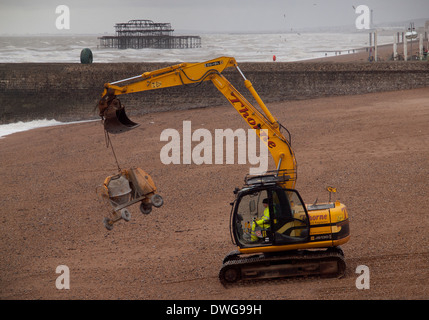 Ein JCB Bagger dient für Reparaturen an einer Buhne am Strand von Brighton Stockfoto