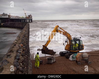 Ein JCB Bagger dient für Reparaturen an einer Buhne am Strand von Brighton Stockfoto