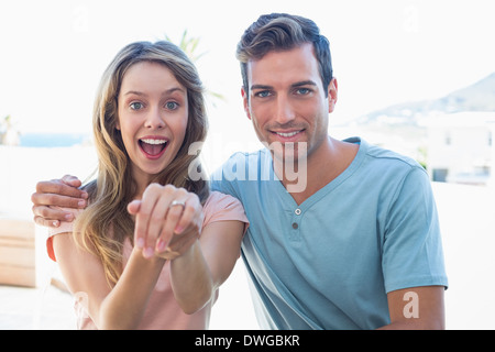 Stets gut gelaunte Frau zeigt Verlobungsring neben Mann Stockfoto