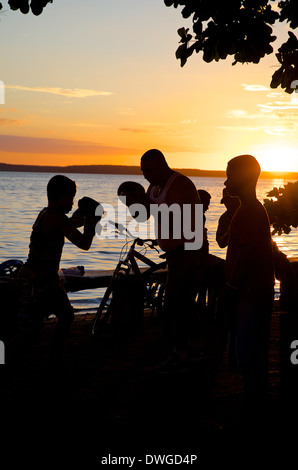 Schatten der junge Boxer Unterrichtseinheiten mit Instruktor in den Sonnenuntergang am Meer entlang in Cienfuegos, Kuba Stockfoto
