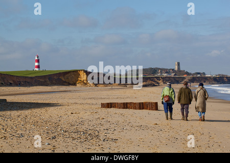 Happisburgh, Norfolk. England. VEREINIGTES KÖNIGREICH. Winter-Strand zu Fuß. Leuchtturm, Kirche und Dorf am Horizont. Stockfoto