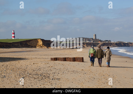 Happisburgh, Norfolk. England. VEREINIGTES KÖNIGREICH. Winter-Strand zu Fuß. Leuchtturm, Kirche und Dorf am Horizont. Stockfoto