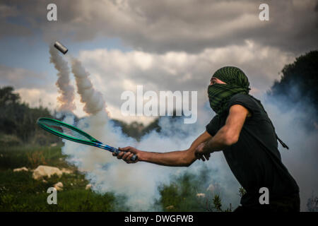 Westjordanland, Palästinensische Gebiete. 7. März 2014. Ein palästinensischen Demonstranten verwendet eine Tennis-Rakete, die Tränengas wieder zurück nach der israelischen Armee während einer gewaltfreien Demonstration im Westjordanland. Dieses Bild zeigt, dass die kreativ-Aktivisten Differents Taktiken verwenden, um sich von Gasflaschen zu schützen, die tödlich verlaufen können. Bildnachweis: Hamde Abu Rahma/NurPhoto/ZUMAPRESS.com/Alamy Live-Nachrichten Stockfoto