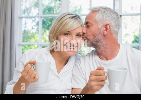 Reifer Mann küsst Frau bei Kaffee im Bett Stockfoto