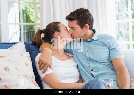 Liebendes Paar küssen im Wohnzimmer Stockfoto