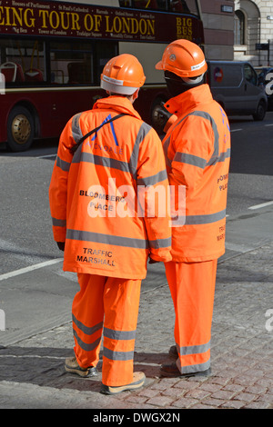 Zwei von einer Art Verkehr hohe Sichtbarkeit Marschalls in der Wartezeit, um das Entladen von Fahrzeugen vor der Baustelle in London England UK zu überwachen Stockfoto