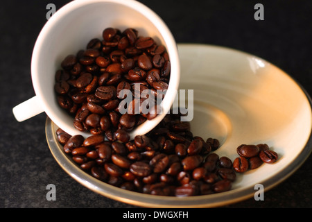 Eine Nahaufnahme von einer Kaffeetasse auf eine Untertasse mit Kaffee Bohnen verschütten von ihm Stockfoto