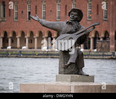 Statue von Evert Taube (1890-1976), der schwedische Autor, Interpret, Komponist und Sänger, auf Riddarholmen, Stockholm, Schweden. Hintergrund ist City Hall. Stockfoto