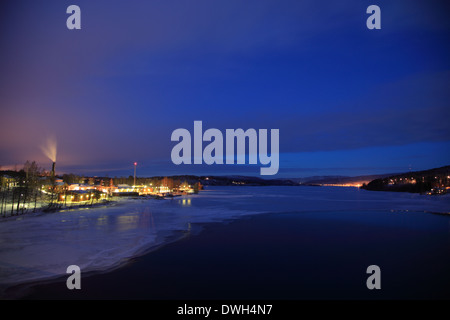 Kraftwerk emittierende Dämpfe in der Nacht am Ufer des zugefrorenen Fluss Angermanaelv in Vaesternorrland, Schweden. Stockfoto