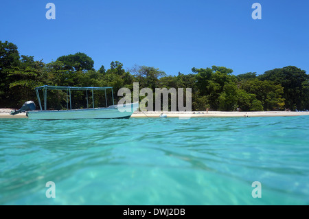 Von der Wasseroberfläche Boot am Liegeplatz Boje in der Nähe von einem unberührten tropischen Strand mit wenigen Touristen, Karibik Stockfoto