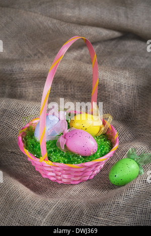 Bunte Ostereier Korb auf Sackleinen Hintergrund Stockfoto