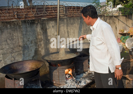 Ein Koch ist Suppe mit einer Kelle rühren, wie er traditionelle Khmer-Suppe in großer Wok auf einer Stadtstraße in Kampong Cham, Kambodscha kocht Stockfoto