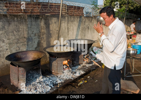 Ein Koch ist Suppe aus einer Kelle schlürfen, wie er traditionelle Khmer-Suppe in großer Wok auf einer Stadtstraße in Kampong Cham, Kambodscha kocht. Stockfoto