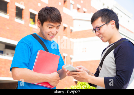 zwei Studenten, die mit einem Handy, auf dem Campus zu diskutieren Stockfoto