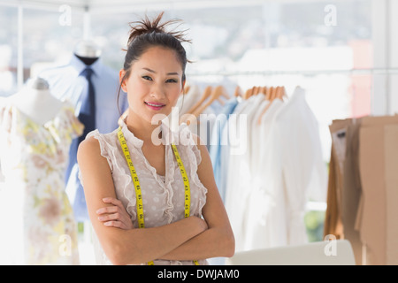 Porträt einer schönen weiblichen Modedesignerin mit Rack von Kleidung Stockfoto