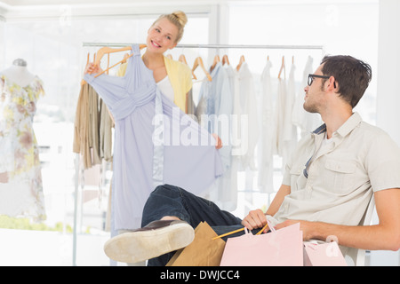 Mann mit Einkaufstüten, während die Frau eine Kleid auswählen Stockfoto