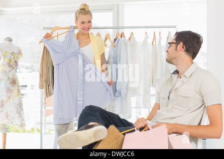 Mann mit Einkaufstüten, während die Frau eine Kleid auswählen Stockfoto