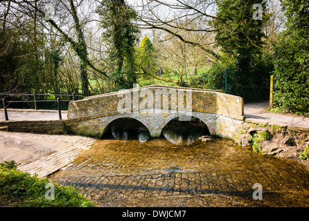 Eine steinerne Brücke Ror Fußgänger überquert einen seichten Bach in Lacock Dorf Wiltshire UK Stockfoto