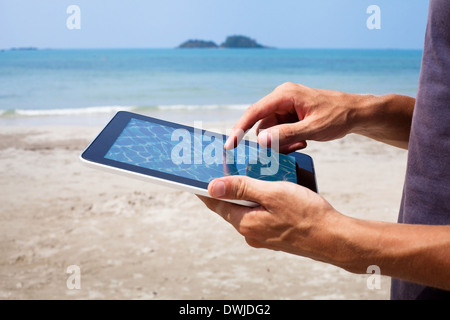 Hände mit Tablet am Strand Stockfoto