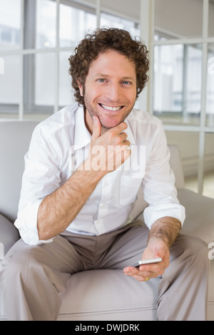 Gut gekleidete junge Mann sitzt zu Hause auf sofa Stockfoto