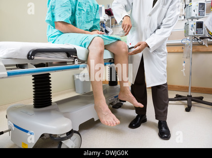 Neurologen untersuchen Knie des Patienten mit Hammer im Krankenhaus Stockfoto